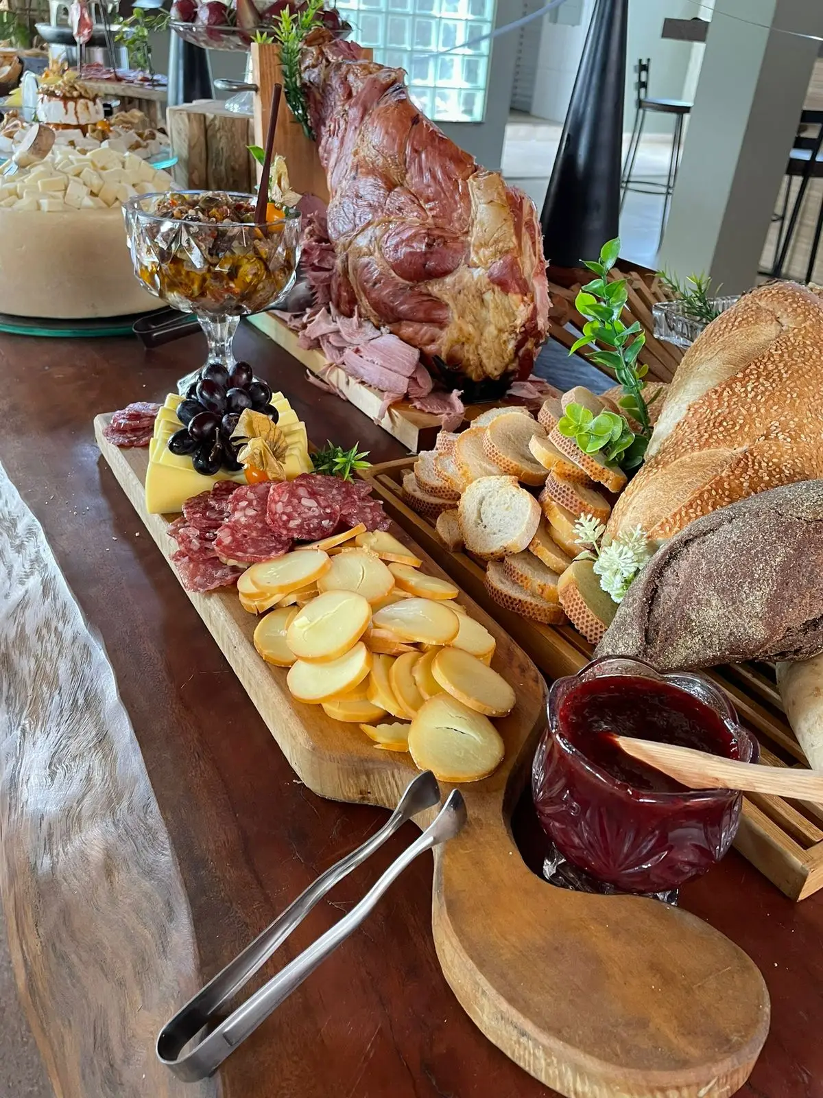 Mesa de antepastos com frios, pães, queijos e peça defumada